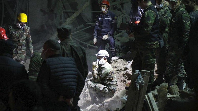 Soldiers and firefighters search for survivors in a residential area that was hit by rocket fire overnight by Armenian forces, early Saturday, Oct. 17, 2020, in Gyanga, Azerbaijan's second largest city, near the border with Armenia. (AP Photo/Aziz Karimov)