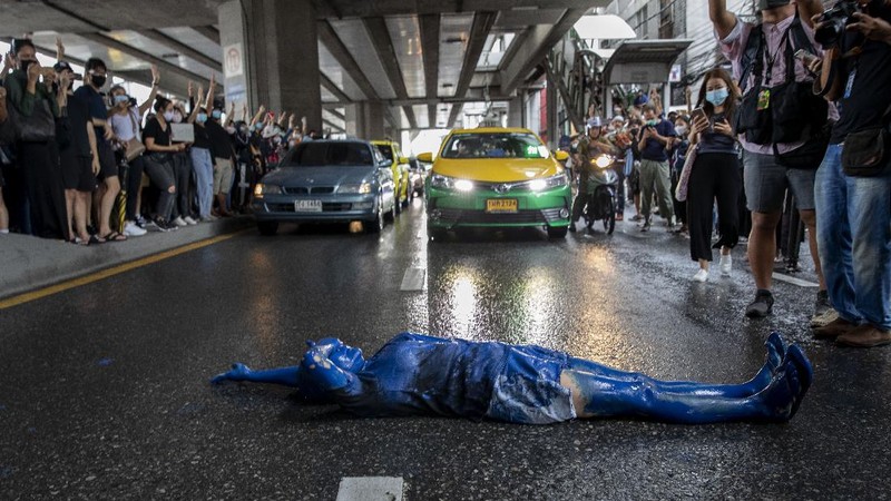 A pro-democracy protester covered in blue paint lies on a road during a protest in Udom Suk, suburbs of Bangkok, Thailand, Saturday, Oct. 17, 2020. The authorities in Bangkok shut down mass transit systems and set up roadblocks Saturday as Thailand’s capital faced a fourth straight day of determined anti-government protests. (AP Photo/Gemunu Amarasinghe)