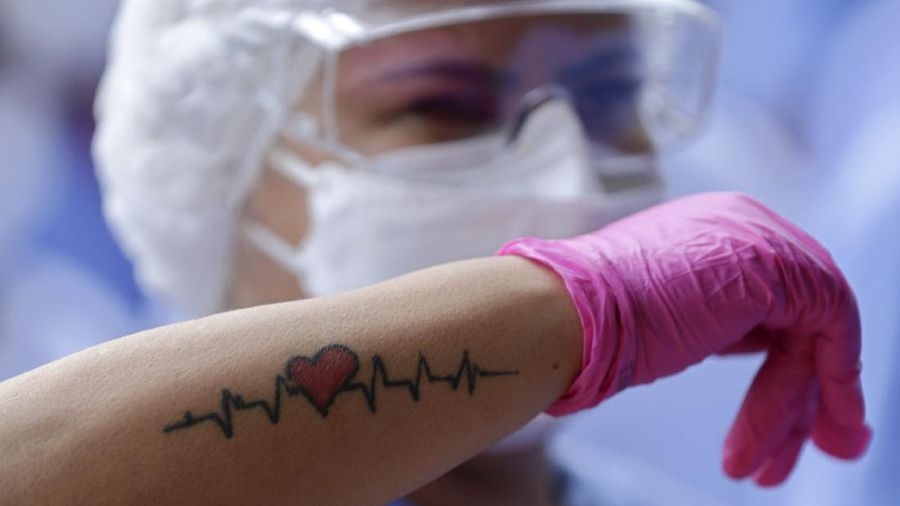 A medical worker shows her life sign tattoo while she and fellow workers celebrate as the last three patients are released from a field hospital at the National Stadium Mane Garrincha, after recuperating from COVID-19, in Brasilia, Brazil, Thursday, Oct. 15, 2020. (AP Photo/Eraldo Peres)