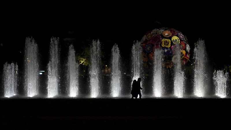 People walk in the empty center of Lyon, central France, Saturday, Oct. 17, 2020. France is deploying 12,000 police officers to enforce a new curfew that came into effect Friday night for the next month to slow the virus spread, and will spend another 1 billion euros to help businesses hit by the new restrictions. (AP Photo/Laurent Cipriani)