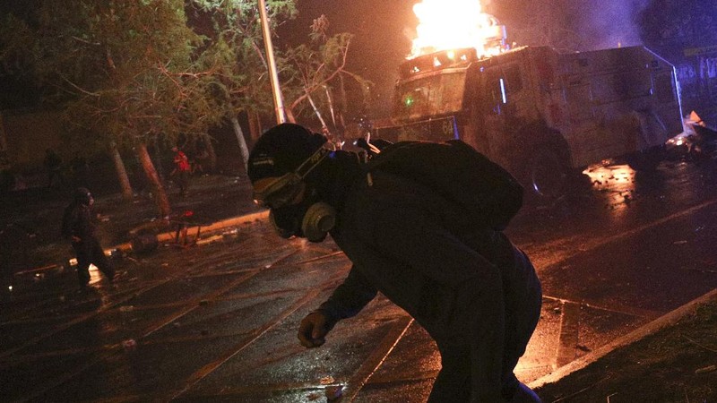 Demonstrators run as police uses water cannons to disperse them on the one-year anniversary of the start of anti-government mass protests over inequality in Santiago, Chile, Sunday, Oct. 18, 2020. (AP Photo/Esteban Felix)