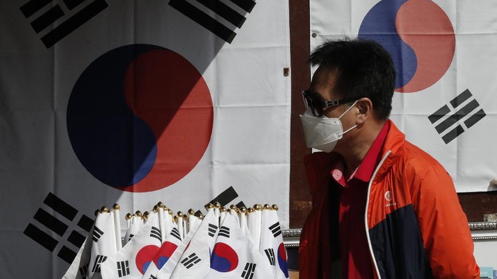A man wearing a face mask walks near national flags displayed at a souvenir shop at the Imjingak Pavilion in Paju, South Korea, Sunday, Oct. 11, 2020. North Korean leader Kim Jong Un warned that his country would 