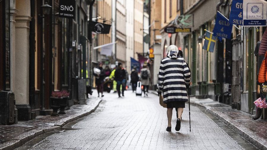 An elderly woman strolls in the Old Town of Stockholm, Sweden, Thursday Oct. 22, 2020. The Swedish government has removed specific coronavirus pandemic recommendations for people aged over 70 and other risk groups despite increasing spread of the virus, due to the mental and physical health risks of isolation. (Amir Nabizadeh / TT via AP)