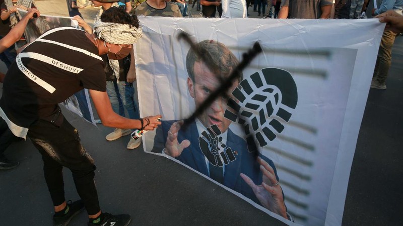 Seorang pria memegang gambar Macron dengan cetakan sepatu di atasnya ketika pengunjuk rasa Turki meneriakkan slogan-slogan menentang Prancis selama demonstrasi atas kartun Nabi Muhammad, di Istanbul. (AP/Adel Hana)