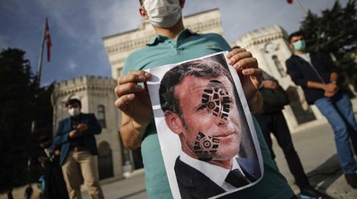 Seorang pria memegang gambar Macron dengan cetakan sepatu di atasnya ketika pengunjuk rasa Turki meneriakkan slogan-slogan menentang Prancis selama demonstrasi atas kartun Nabi Muhammad, di Istanbul. (AP/Adel Hana)