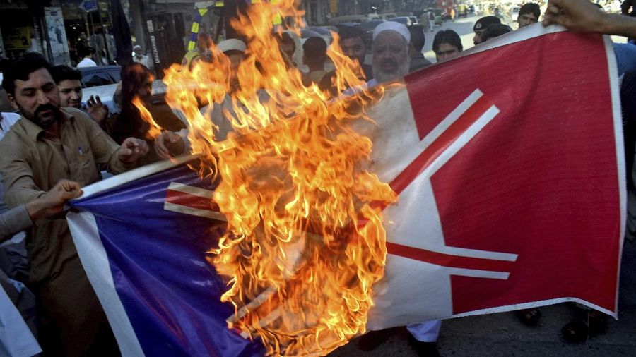 Seorang pria memegang gambar Macron dengan cetakan sepatu di atasnya ketika pengunjuk rasa Turki meneriakkan slogan-slogan menentang Prancis selama demonstrasi atas kartun Nabi Muhammad, di Istanbul. (AP/Adel Hana)