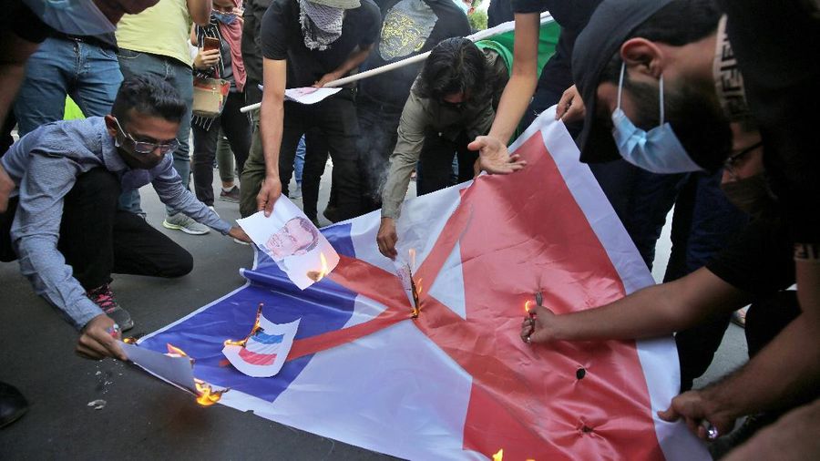 Iranian protesters hold defaced pictures of French President Emmanuel Macron during a protest against Macron and the publishing of caricatures of the Prophet Muhammad they deem blasphemous, in front of French Embassy in Tehran, Iran, Wednesday, Oct. 28, 2020. Macron has vowed his country will not back down from its secular ideals and defense of free speech. (AP Photo/Ebrahim Noroozi)