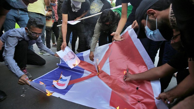 Iranian protesters hold defaced pictures of French President Emmanuel Macron during a protest against Macron and the publishing of caricatures of the Prophet Muhammad they deem blasphemous, in front of French Embassy in Tehran, Iran, Wednesday, Oct. 28, 2020. Macron has vowed his country will not back down from its secular ideals and defense of free speech. (AP Photo/Ebrahim Noroozi)