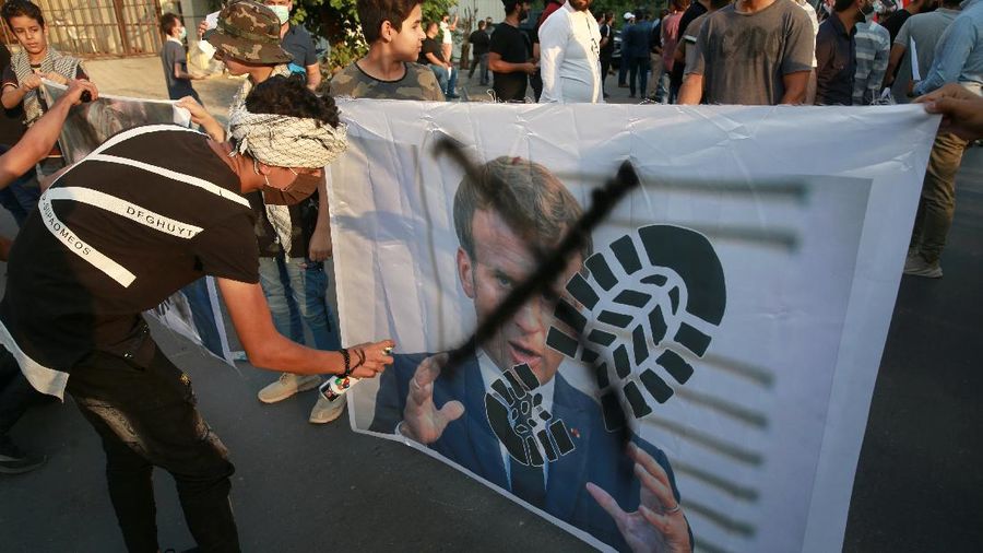 Iranian protesters hold defaced pictures of French President Emmanuel Macron during a protest against Macron and the publishing of caricatures of the Prophet Muhammad they deem blasphemous, in front of French Embassy in Tehran, Iran, Wednesday, Oct. 28, 2020. Macron has vowed his country will not back down from its secular ideals and defense of free speech. (AP Photo/Ebrahim Noroozi)