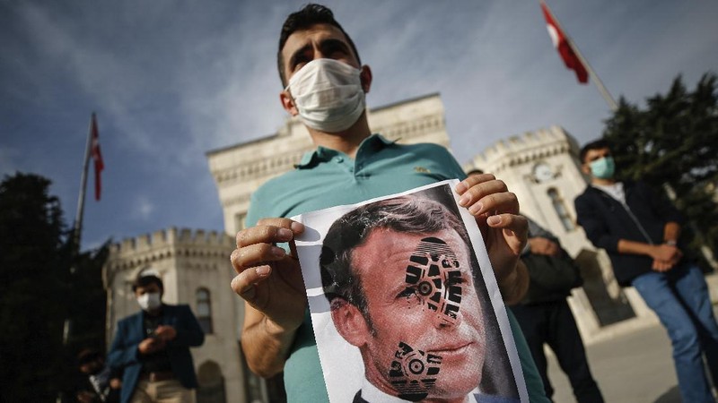 Iranian protesters hold defaced pictures of French President Emmanuel Macron during a protest against Macron and the publishing of caricatures of the Prophet Muhammad they deem blasphemous, in front of French Embassy in Tehran, Iran, Wednesday, Oct. 28, 2020. Macron has vowed his country will not back down from its secular ideals and defense of free speech. (AP Photo/Ebrahim Noroozi)