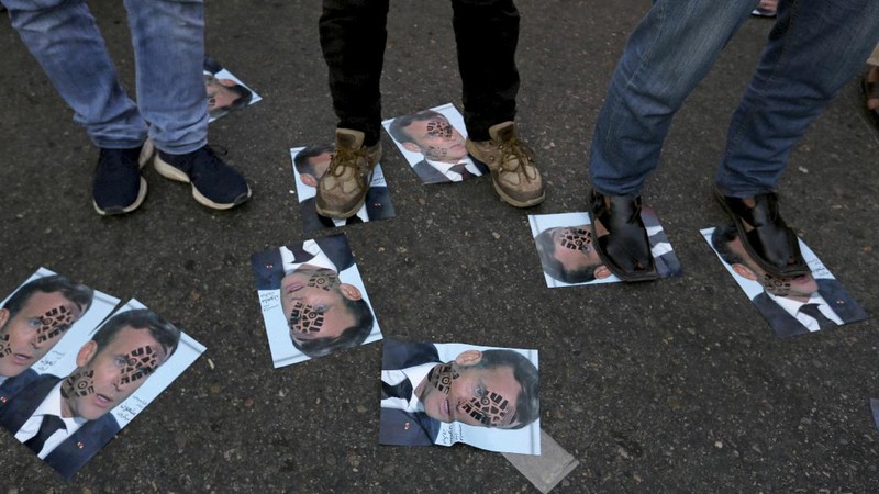 Iranian protesters hold defaced pictures of French President Emmanuel Macron during a protest against Macron and the publishing of caricatures of the Prophet Muhammad they deem blasphemous, in front of French Embassy in Tehran, Iran, Wednesday, Oct. 28, 2020. Macron has vowed his country will not back down from its secular ideals and defense of free speech. (AP Photo/Ebrahim Noroozi)