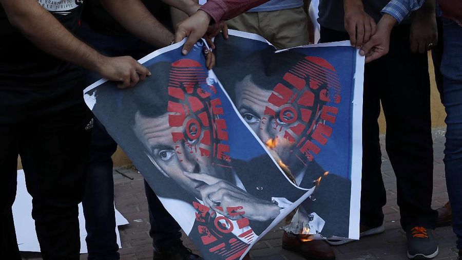 Iranian protesters hold defaced pictures of French President Emmanuel Macron during a protest against Macron and the publishing of caricatures of the Prophet Muhammad they deem blasphemous, in front of French Embassy in Tehran, Iran, Wednesday, Oct. 28, 2020. Macron has vowed his country will not back down from its secular ideals and defense of free speech. (AP Photo/Ebrahim Noroozi)
