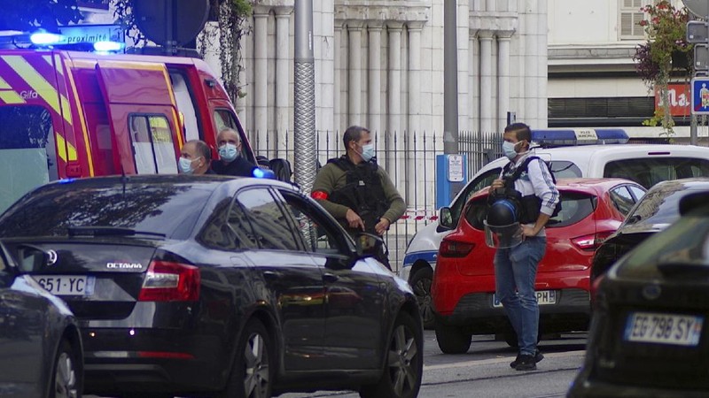 French policemen stand next to Notre Dame church after a knife attack, in Nice, France, Thursday, Oct. 29, 2020. French anti-terrorism prosecutors are investigating a knife attack at a church in the Mediterranean city of Nice that killed two people and injured several others. (AP Photo/Alexis Gilli)