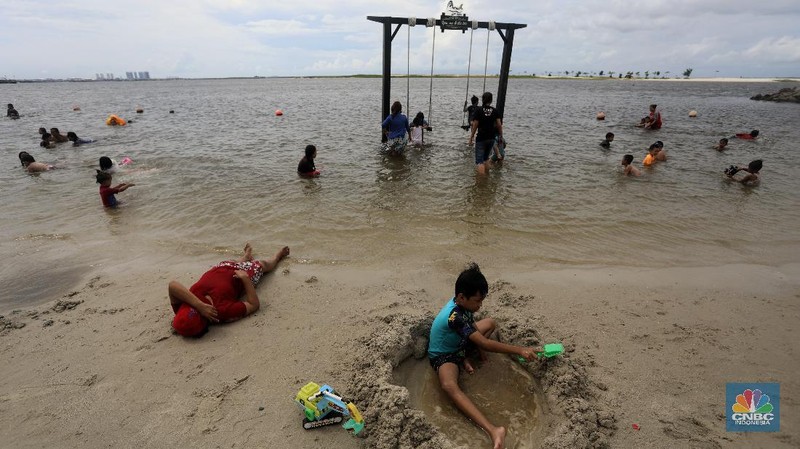 Wisatawan menikmati suasana Pantai Lagoon, Ancol, Jakarta, Jumat (30/10/2020). Libur Nasional dan Cuti bersama dimanfaatkan warga Jakarta untuk bertamasya ke tempat wisata di Jakarta.  (CNBC Indonesia/Andrean Kristianto)