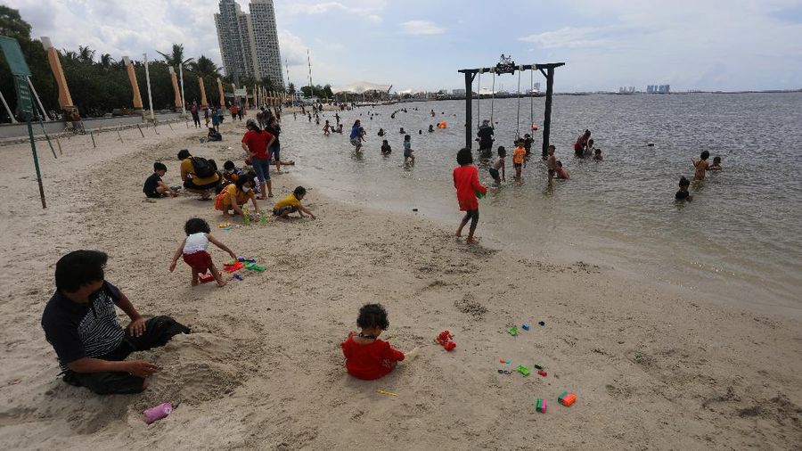 Wisatawan menikmati suasana Pantai Lagoon, Ancol, Jakarta, Jumat (30/10/2020). Libur Nasional dan Cuti bersama dimanfaatkan warga Jakarta untuk bertamasya ke tempat wisata di Jakarta.  (CNBC Indonesia/Andrean Kristianto)