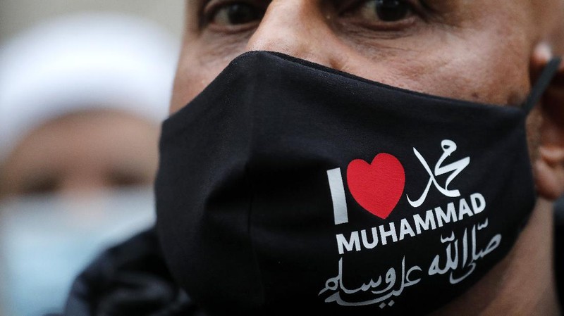 A protester wearing a face mask outside the French embassy in London, Friday, Oct. 30, 2020, to protest against French President Macron. Protesters are upset over the publication of pictures and what they see as disrespect of the Prophet Muhammad, in the wake of the terror attack in Nice, France. (AP Photo/Frank Augstein)