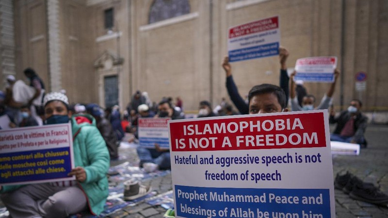 A protester wearing a face mask outside the French embassy in London, Friday, Oct. 30, 2020, to protest against French President Macron. Protesters are upset over the publication of pictures and what they see as disrespect of the Prophet Muhammad, in the wake of the terror attack in Nice, France. (AP Photo/Frank Augstein)