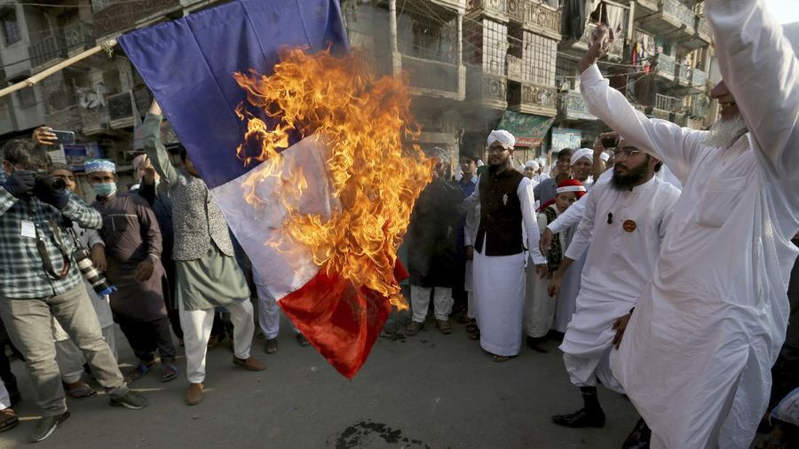 A protester wearing a face mask outside the French embassy in London, Friday, Oct. 30, 2020, to protest against French President Macron. Protesters are upset over the publication of pictures and what they see as disrespect of the Prophet Muhammad, in the wake of the terror attack in Nice, France. (AP Photo/Frank Augstein)