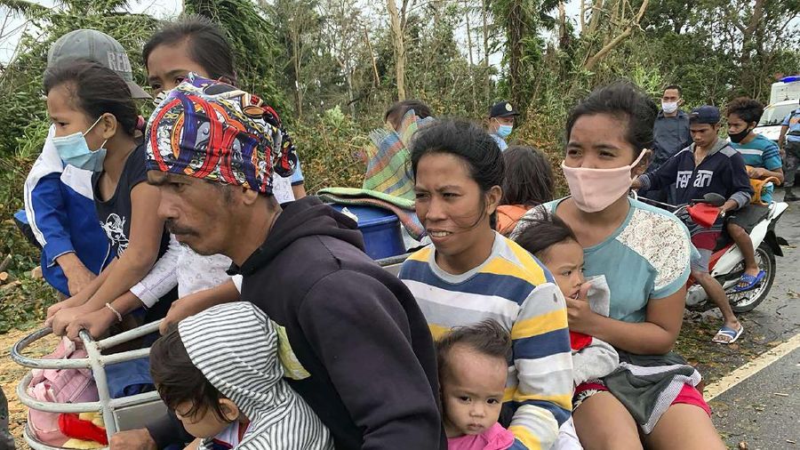 In this photo provided by the Philippine Coast Guard, families are evacuated to safer ground in Camarines Sur province, eastern Philippines on Saturday Oct. 31, 2020 as they prepare for typhoon Goni. Families living near coastal towns have started moving to evacuation centers as the strong typhoon approaches the country. (Philippine Coast Guard via AP)