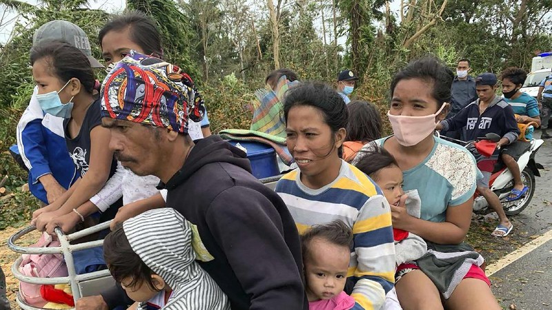 In this photo provided by the Philippine Coast Guard, families are evacuated to safer ground in Camarines Sur province, eastern Philippines on Saturday Oct. 31, 2020 as they prepare for typhoon Goni. Families living near coastal towns have started moving to evacuation centers as the strong typhoon approaches the country. (Philippine Coast Guard via AP)