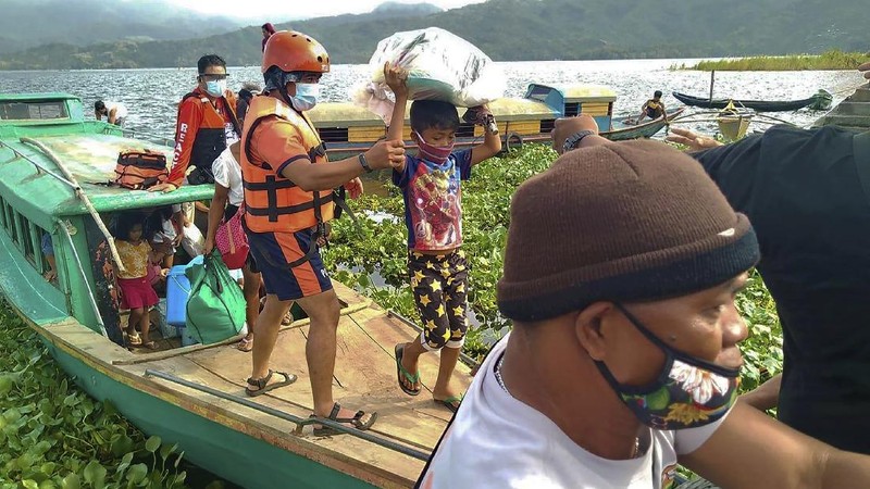 In this photo provided by the Philippine Coast Guard, families are evacuated to safer ground in Camarines Sur province, eastern Philippines on Saturday Oct. 31, 2020 as they prepare for typhoon Goni. Families living near coastal towns have started moving to evacuation centers as the strong typhoon approaches the country. (Philippine Coast Guard via AP)