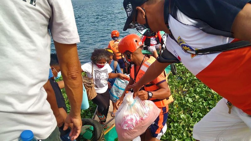 In this photo provided by the Philippine Coast Guard, families are evacuated to safer ground in Camarines Sur province, eastern Philippines on Saturday Oct. 31, 2020 as they prepare for typhoon Goni. Families living near coastal towns have started moving to evacuation centers as the strong typhoon approaches the country. (Philippine Coast Guard via AP)