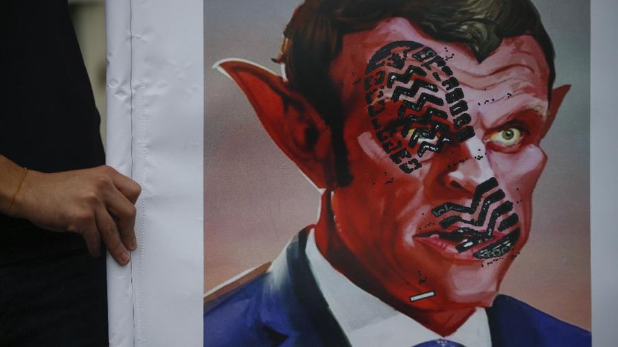 A protester wearing a face mask outside the French embassy in London, Friday, Oct. 30, 2020, to protest against French President Macron. Protesters are upset over the publication of pictures and what they see as disrespect of the Prophet Muhammad, in the wake of the terror attack in Nice, France. (AP Photo/Frank Augstein)