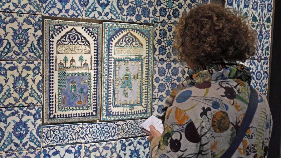 A member of the media examines a ceramic tile wall displayed at the Louvre museum in Paris, Thursday Sept. 20, 2012. The Louvre museum is unveiling its new wing and galleries dedicated to the arts of Islam, and new dragon-fly shaped building marking the museum's greatest development since the iconic glass pyramid constructed twenty years ago.(AP Photo/Remy de la Mauviniere)