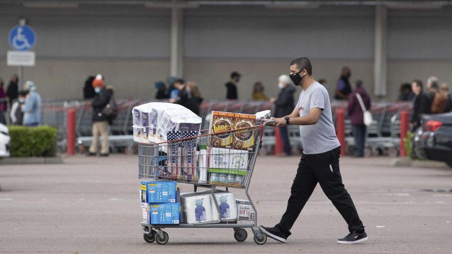 One shopper walks away with a full cart as others queue outside a major supermarket in Leicester, England, Sunday Nov. 1, 2020. The British government announced on Saturday a four-week public lockdown in response to the latest coronavirus surge, and government lawmaker Michael Gove on Sunday acknowledged that the lockdown could be extended. (Joe Giddens/PA via AP)