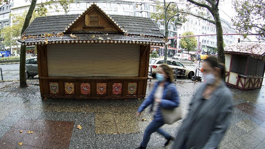 Two woman walk past closed Christmas market booths on the famous shopping road