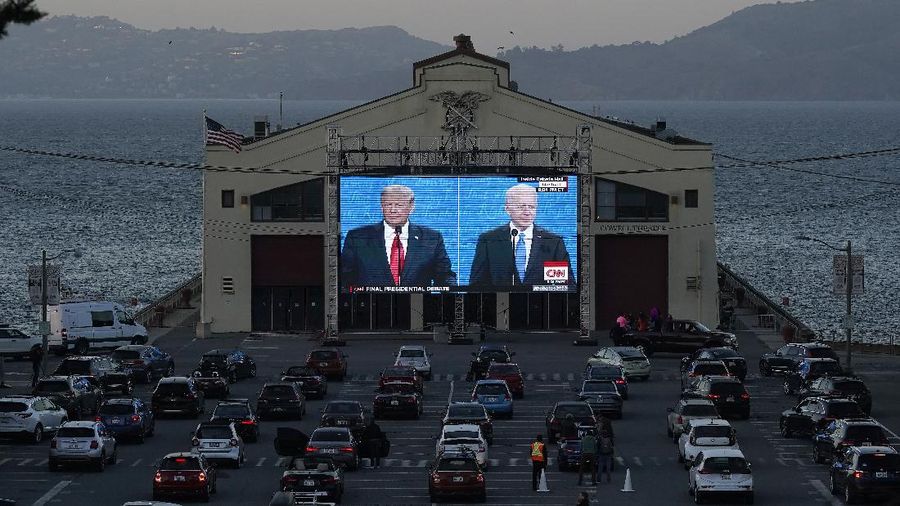 People watch from their vehicles as President Donald Trump, on left of video screen, and Democratic presidential candidate former Vice President Joe Biden speak during a Presidential Debate Watch Party at Fort Mason Center in San Francisco, Thursday, Oct. 22, 2020. The debate party was organized by Manny's, a San Francisco community meeting and learning place. (AP Photo/Jeff Chiu)