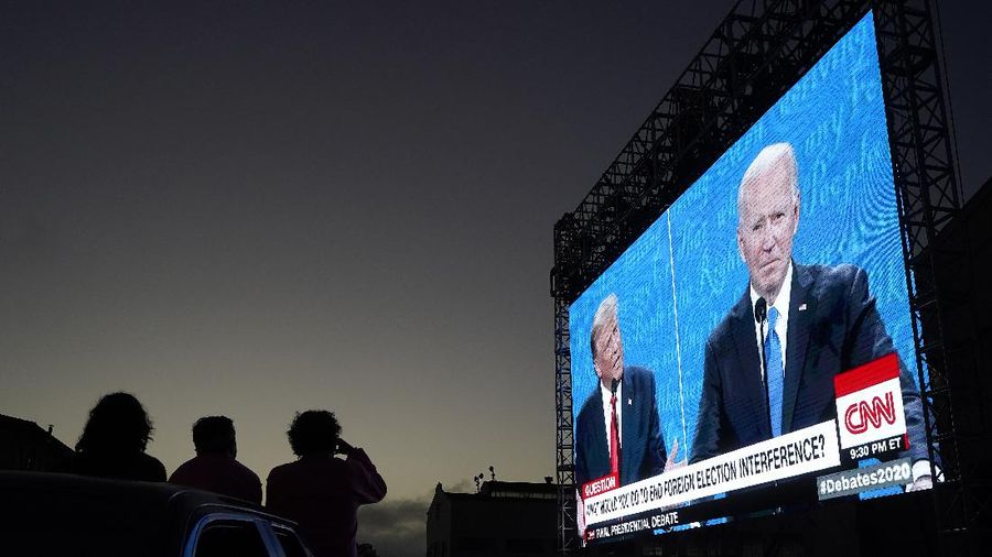 People watch from their vehicle as President Donald Trump, on left of video screen, and Democratic presidential candidate former Vice President Joe Biden speak during a Presidential Debate Watch Party at Fort Mason Center in San Francisco, Thursday, Oct. 22, 2020. The debate party was organized by Manny's, a San Francisco community meeting and learning place. (AP Photo/Jeff Chiu)