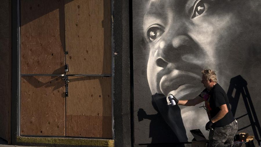 Artist Shane Grammar paints a portrait of Martin Luther King Jr. on the sheets of plywood outside a boarded-up jewelry shop amid worries about potential demonstrations and violent responses to the general election on Monday, Nov. 2, 2020, in Los Angeles. (AP Photo/Jae C. Hong)