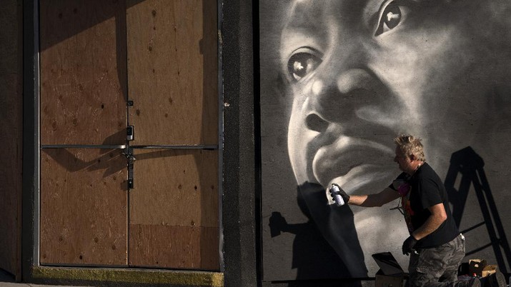 Artist Shane Grammar paints a portrait of Martin Luther King Jr. on the sheets of plywood outside a boarded-up jewelry shop amid worries about potential demonstrations and violent responses to the general election on Monday, Nov. 2, 2020, in Los Angeles. (AP Photo/Jae C. Hong)