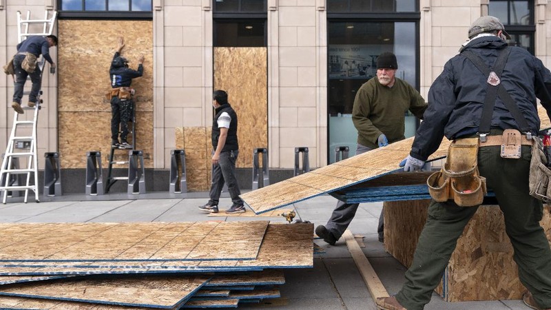 Artist Shane Grammar paints a portrait of Martin Luther King Jr. on the sheets of plywood outside a boarded-up jewelry shop amid worries about potential demonstrations and violent responses to the general election on Monday, Nov. 2, 2020, in Los Angeles. (AP Photo/Jae C. Hong)