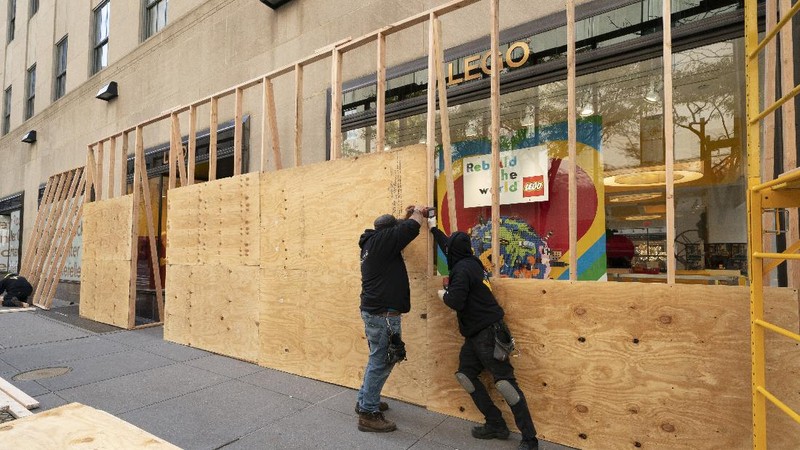 Artist Shane Grammar paints a portrait of Martin Luther King Jr. on the sheets of plywood outside a boarded-up jewelry shop amid worries about potential demonstrations and violent responses to the general election on Monday, Nov. 2, 2020, in Los Angeles. (AP Photo/Jae C. Hong)