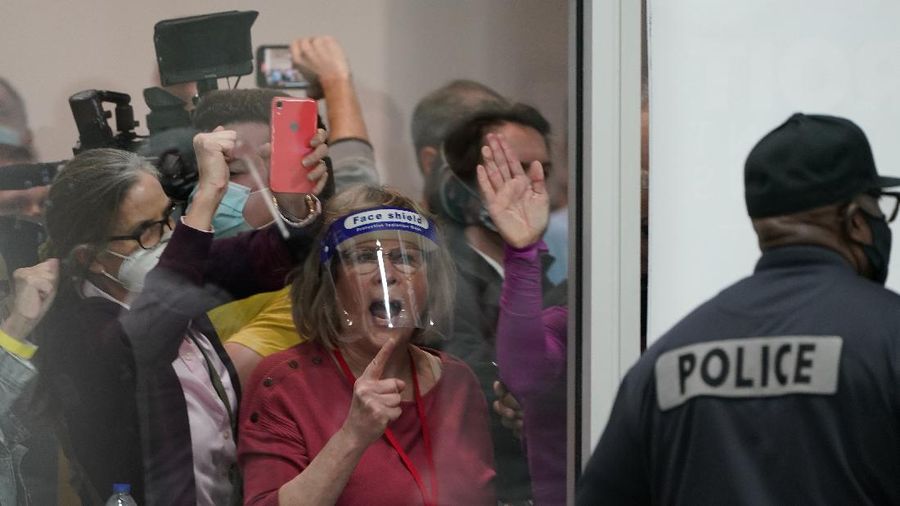 Election challengers yell as they look through the windows of the central counting board as police were helping to keep additional challengers from entering due to overcrowding, Wednesday, Nov. 4, 2020, in Detroit. (AP Photo/Carlos Osorio)