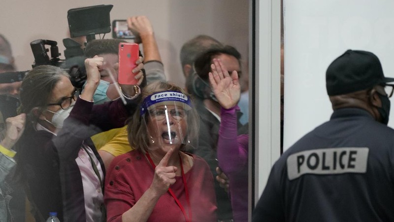 Election challengers yell as they look through the windows of the central counting board as police were helping to keep additional challengers from entering due to overcrowding, Wednesday, Nov. 4, 2020, in Detroit. (AP Photo/Carlos Osorio)