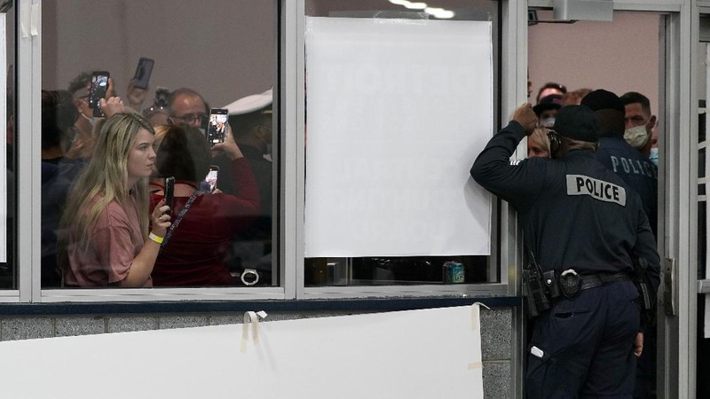 Election challengers yell as they look through the windows of the central counting board as police were helping to keep additional challengers from entering due to overcrowding, Wednesday, Nov. 4, 2020, in Detroit. (AP Photo/Carlos Osorio)
