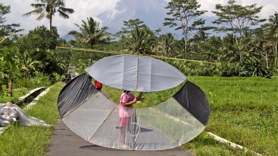 A farmer walks on his field as Mount Merapi is seen in the background in Sleman, Indonesia, Thursday, Nov. 5, 2020. Indonesian authorities raised the danger level for the volatile Mount Merapi volcano on the densely populated island of Java on Thursday and ordered a halt to tourism and mining activities. (AP Photo/Slamet Riyadi)
