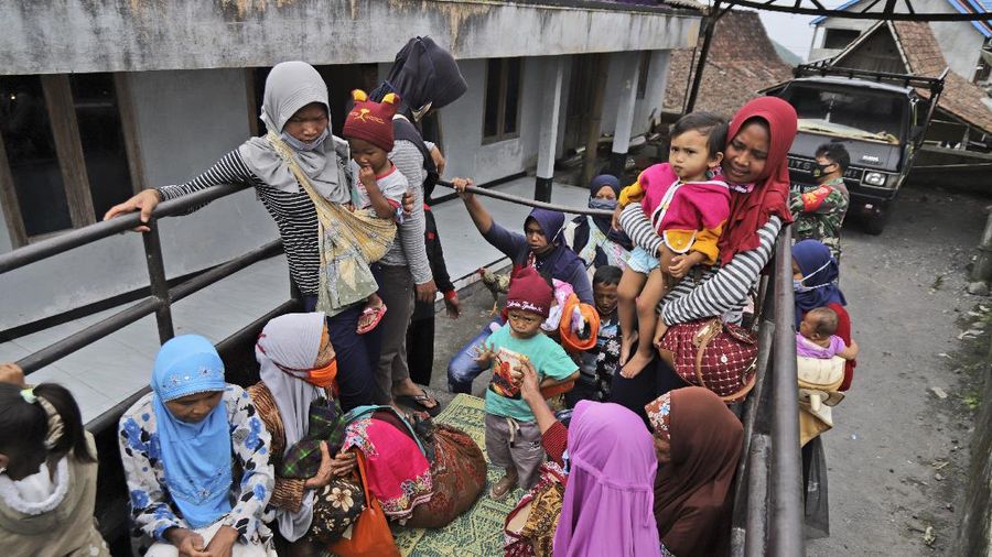 Villagers sit on the back of a truck as they are evacuated from their homes on the slope of Mount Merapi, in Krinjing, Central Java, Indonesia, Friday, Nov. 6, 2020. Indonesian authorities began evacuating people living on the volatile volcano's fertile slopes on Friday following an increase in volcanic activity. (AP Photo/Taufiq Rozzaq)