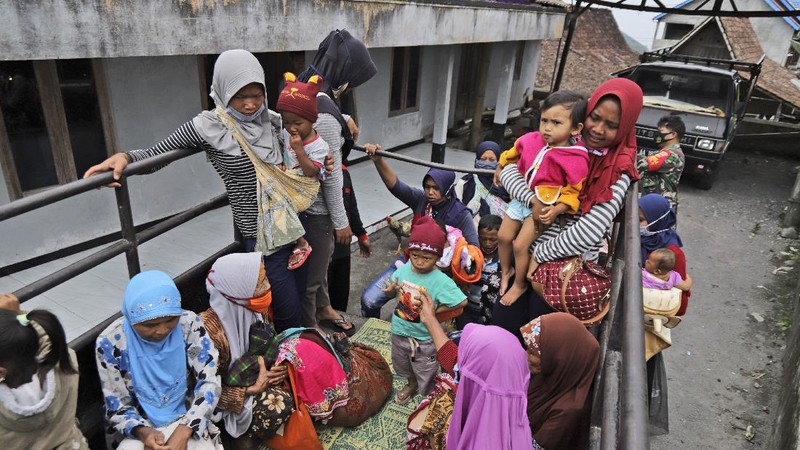 Villagers sit on the back of a truck as they are evacuated from their homes on the slope of Mount Merapi, in Krinjing, Central Java, Indonesia, Friday, Nov. 6, 2020. Indonesian authorities began evacuating people living on the volatile volcano's fertile slopes on Friday following an increase in volcanic activity. (AP Photo/Taufiq Rozzaq)
