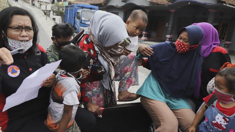 Villagers sit on the back of a truck as they are evacuated from their homes on the slope of Mount Merapi, in Krinjing, Central Java, Indonesia, Friday, Nov. 6, 2020. Indonesian authorities began evacuating people living on the volatile volcano's fertile slopes on Friday following an increase in volcanic activity. (AP Photo/Taufiq Rozzaq)