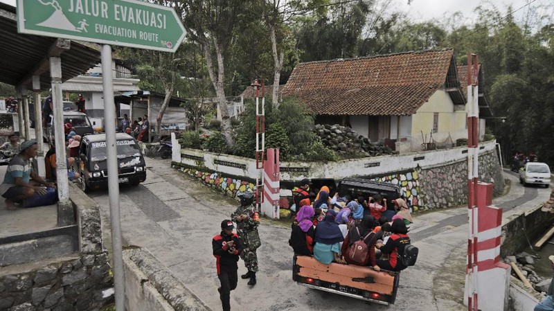 Villagers sit on the back of a truck as they are evacuated from their homes on the slope of Mount Merapi, in Krinjing, Central Java, Indonesia, Friday, Nov. 6, 2020. Indonesian authorities began evacuating people living on the volatile volcano's fertile slopes on Friday following an increase in volcanic activity. (AP Photo/Taufiq Rozzaq)