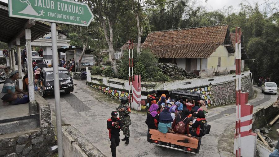 Villagers sit on the back of a truck as they are evacuated from their homes on the slope of Mount Merapi, in Krinjing, Central Java, Indonesia, Friday, Nov. 6, 2020. Indonesian authorities began evacuating people living on the volatile volcano's fertile slopes on Friday following an increase in volcanic activity. (AP Photo/Taufiq Rozzaq)