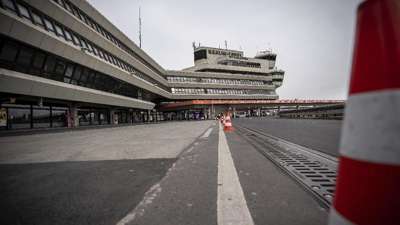 A staff member looks at a departure and arrival information board in an abandoned terminal at the airport Tegel in Berlin, Germany, Monday, June 15, 2020. Borders opened up across Europe on Monday after three months of coronavirus closures that began chaotically in March. But many restrictions persist, it's unclear how keen Europeans will be to travel this summer and the continent is still closed to Americans, Asians and other international tourists. (AP Photo/Michael Sohn)