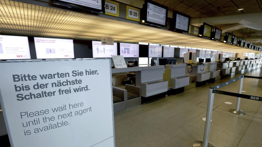 A staff member looks at a departure and arrival information board in an abandoned terminal at the airport Tegel in Berlin, Germany, Monday, June 15, 2020. Borders opened up across Europe on Monday after three months of coronavirus closures that began chaotically in March. But many restrictions persist, it's unclear how keen Europeans will be to travel this summer and the continent is still closed to Americans, Asians and other international tourists. (AP Photo/Michael Sohn)