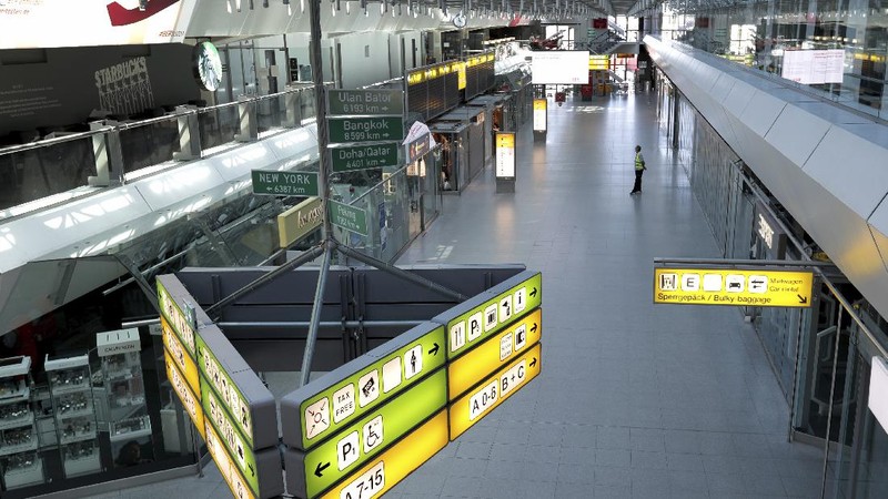 A staff member looks at a departure and arrival information board in an abandoned terminal at the airport Tegel in Berlin, Germany, Monday, June 15, 2020. Borders opened up across Europe on Monday after three months of coronavirus closures that began chaotically in March. But many restrictions persist, it's unclear how keen Europeans will be to travel this summer and the continent is still closed to Americans, Asians and other international tourists. (AP Photo/Michael Sohn)