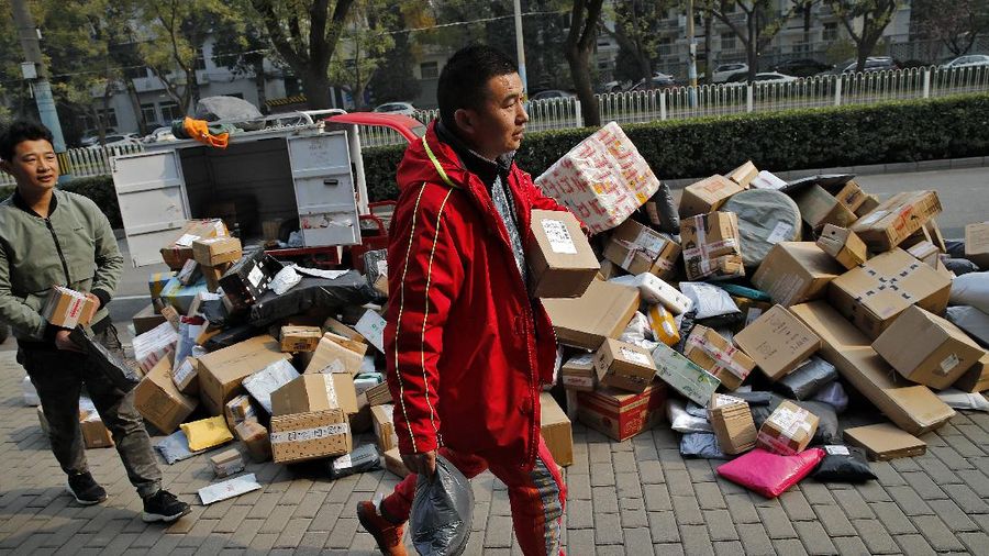 Delivery workers sort out parcels piling up at a pickup point near a residential apartment buildings in Beijing, Wednesday, Nov. 11, 2020. Chinese consumers are expected to spend tens of billions on everything from fresh food to luxury goods during this year's Singles' Day online shopping festival, as the country recovers from the pandemic. (AP Photo/Andy Wong)