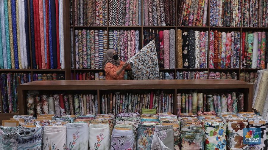 Pedagang beraktivitas di salah satu gerai kain di Pasar Mayestik, Jakarta, Rabu (11/11/2020). Pasar dalam negeri kembali dibanjiri oleh produk impor baik dalam bentuk kain maupun pakaian jadi di tengah lesunya industri domestik. Sengkarut industri tekstil terkait masalah impor masih belum berkesudahan. Saat ini ada tarik-tarikan kepentingan antara pelaku usaha industri soal mekanisme impor bahan baku yang efeknya bisa berbeda dari masing-masing industri hulu dan hilir. mengutip berita CNBC Indonesia pada 10 November, Kementerian Perdagangan dikabarkan bakal merevisi Peraturan Menteri Perdagangan (Permendag) mengenai aturan main importasi tekstil. Hal ini tidak lepas dari dorongan industri dalam negeri yang meminta adanya perubahan regulasi dari aturan-aturan yang lama. Maklum, beberapa revisi Permendag yang mengatur impor sejak tahun 2015 dinilai selalu pro barang impor. Pantauan CNBC Indonesia salah satu pemilik toko mengatakan bahwa bahan yang ia beli Grosiran di Bandung, Tasik dan sekitarnya. Namun tidak diketahui dari Mama bahan dasar tekstil itu berasal. Kalangan industri tekstil dan produk tekstil (TPT) termasuk di sektor hulu seperti benang masih mengeluhkan adanya gangguan produk impor. Masih ada persoalan tak harmoninya kebijakan sehingga ada industri yang kena dampak.  (CNBC Indonesia/Muhammad Sabki)